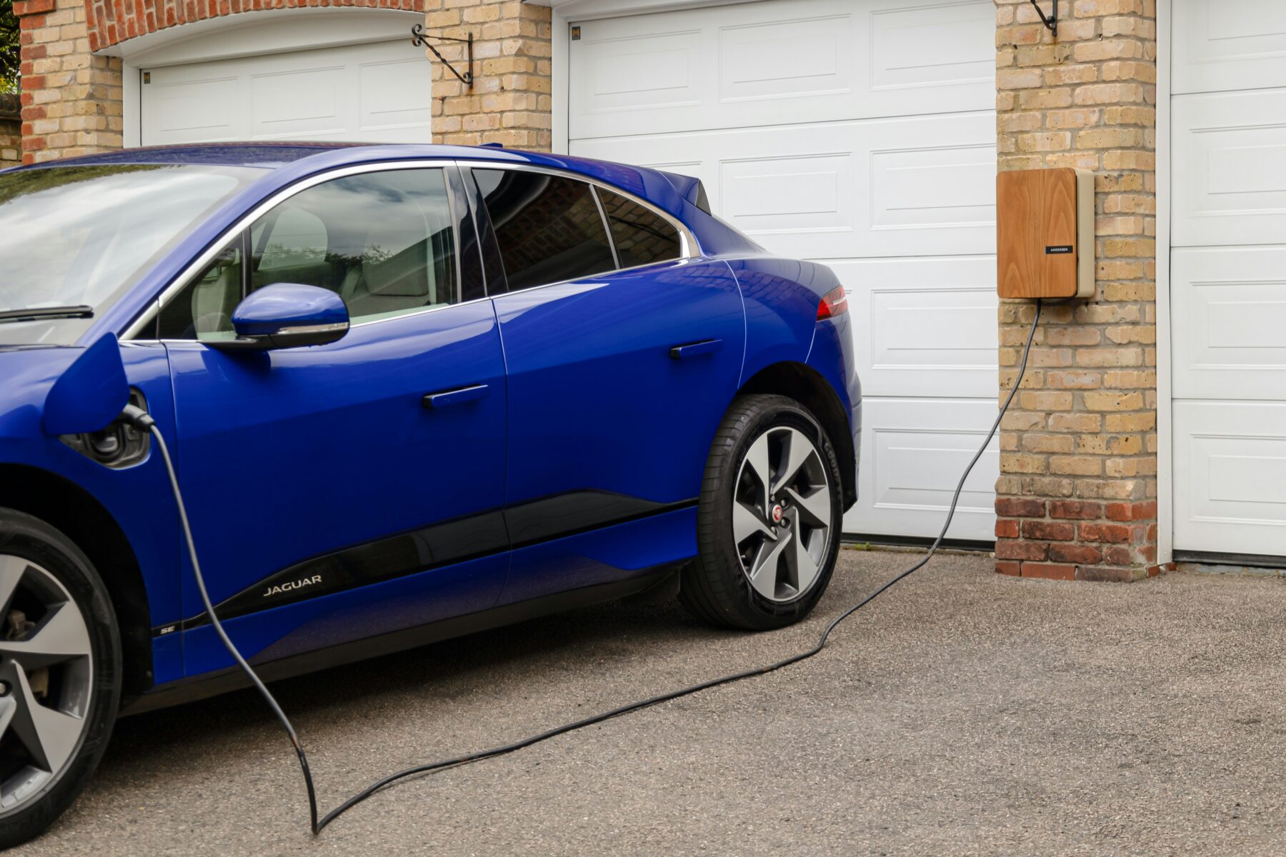 Ein blaues Elektroauto, das an eine Garage angeschlossen ist